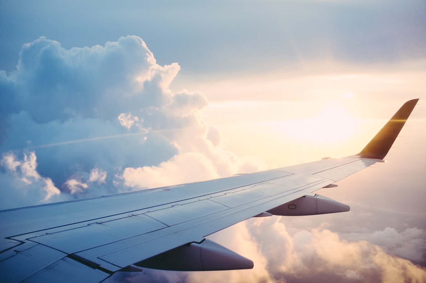 Travel Stories & Inspiration - Airplane wing above clouds